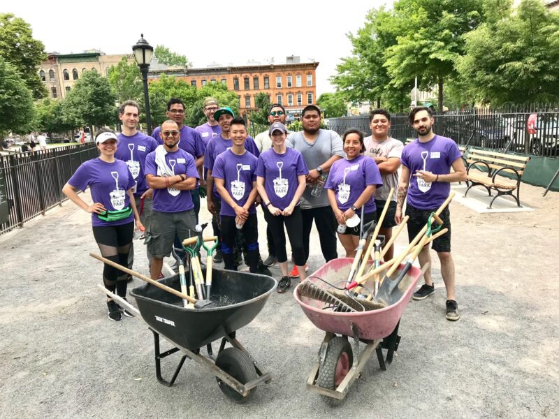 The Maria Hernandez Dog Run Pack, a group of volunteers, pose with their tools, wheelbarrows, and matching purple shirts in the park in 2022. Photo: Amy Willard.