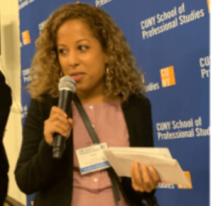 A photo of CUNY SPS grad student Tara Santos holding a microphone at a school event.