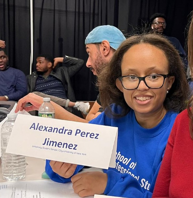 A photo of CUNY SPS Governing Council Rep Alexandra Perez Jimenez at a conference holding up her name plate.