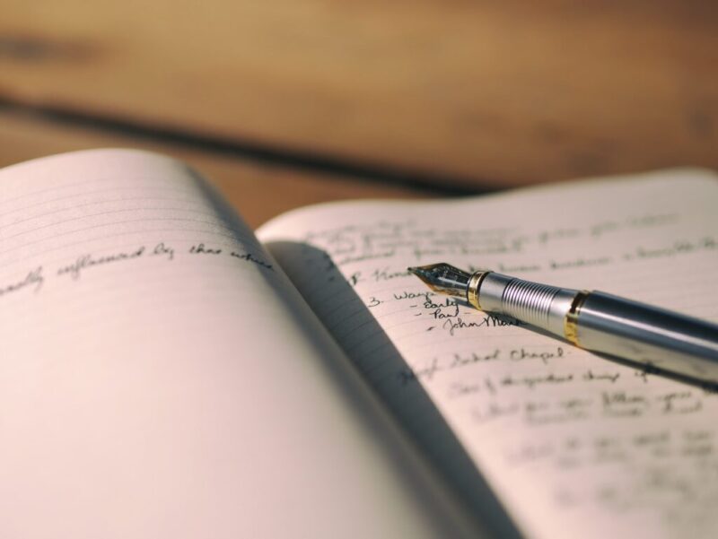 A stock photo of a fountain pen and a notebook up close.