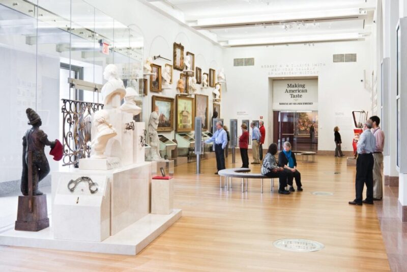 A photo of one of the main galleries at the New-York Historical Society in Manhattan, featuring busts of famous Americans and paintings of American landmarks.
