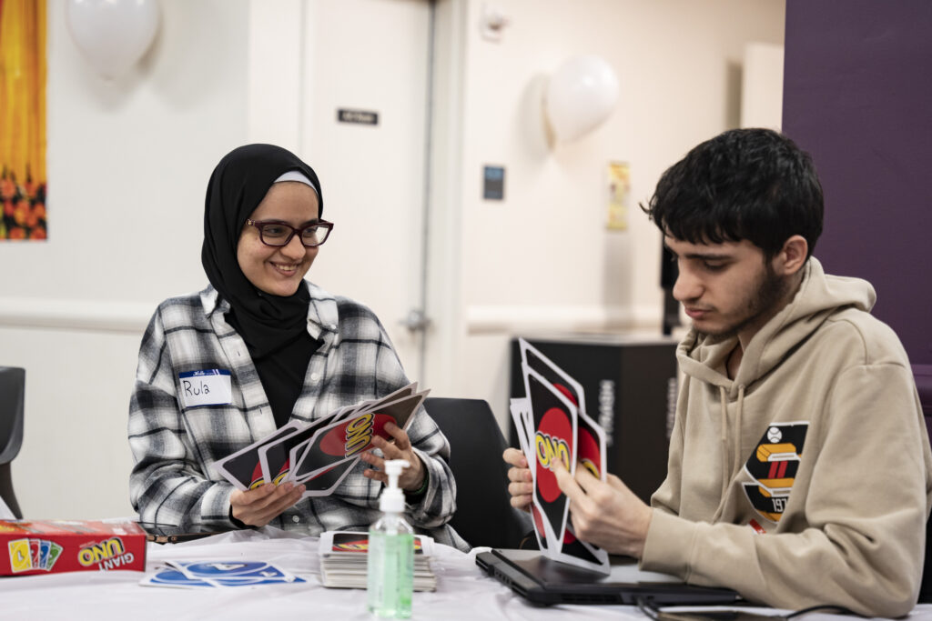 A photo of two students playing Uno with oversized cards during the South Asian Student Union's Iftar event.