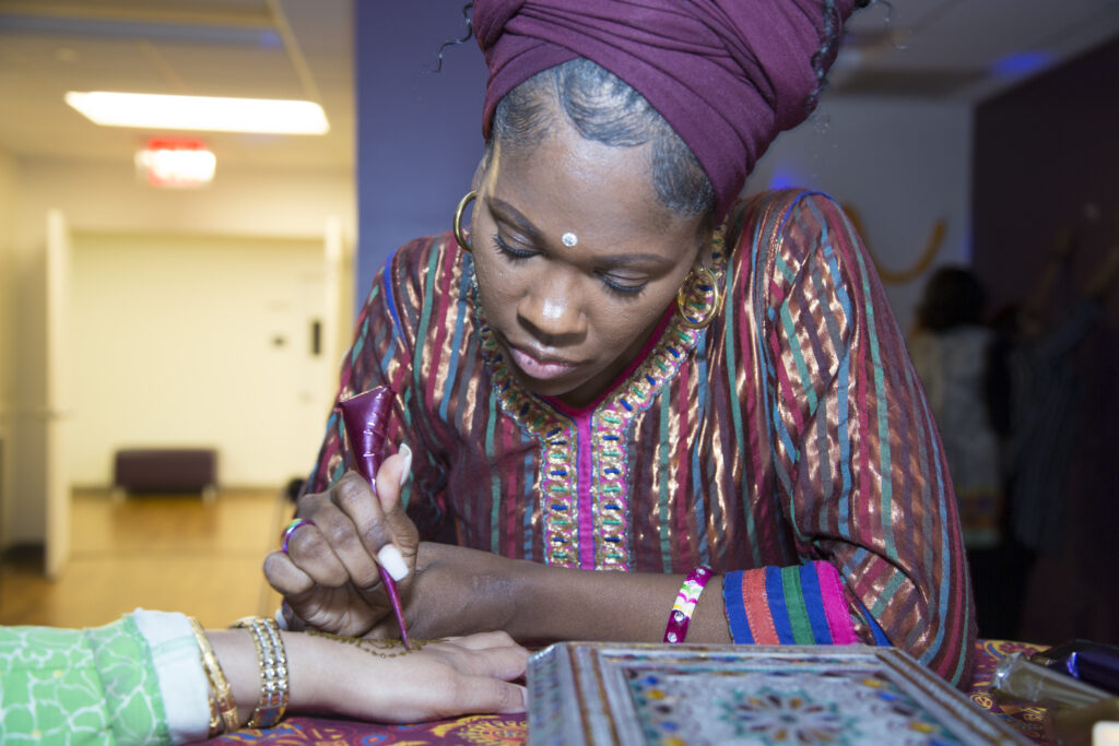 a woman doing a henna design on a hand
