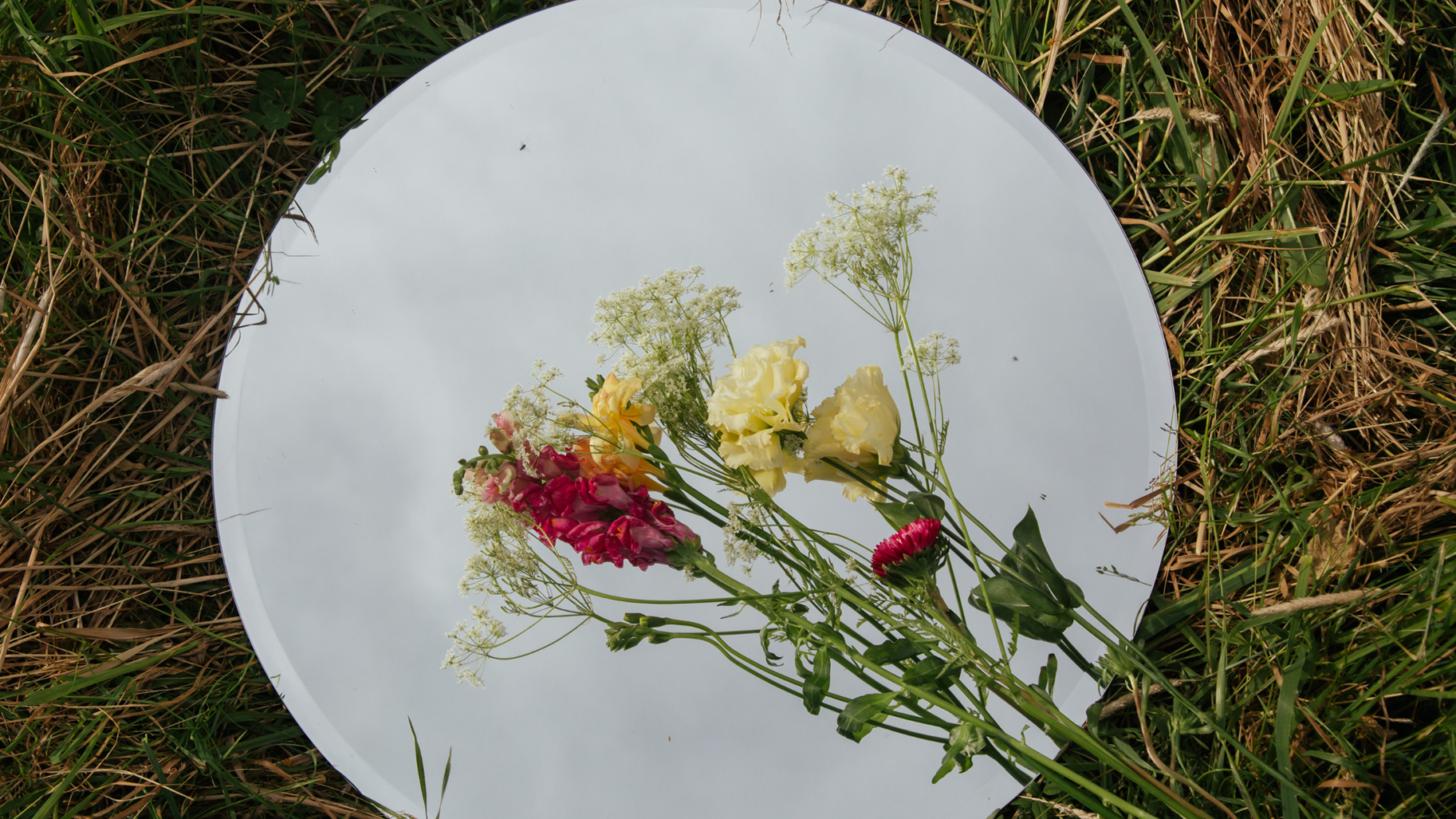 A decorative mirror adorned with colorful flowers around its frame.